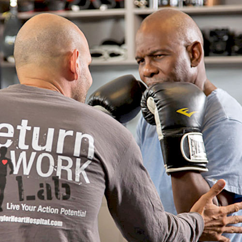 A man trains another man who wears boxing gloves as part of his cardiac rehab