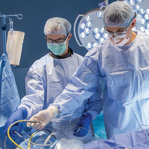Dos cirujanos con batas completas realizan una cirugía en el quirófano.