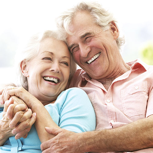 An older man and woman hug each other and smile.